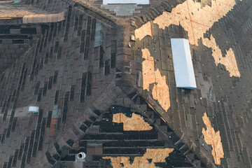 Fototapeta premium Wind damaged house roof with missing asphalt shingles after hurricane Ian in Florida. Repair of home rooftop concept