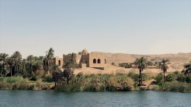 OASIS ON EGYPTIAN DESERT WITH HOUSE ON IN FRONT OF NILO RIVER WITH GREEN PALMS