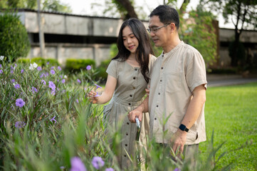 Lovely Asian daughter and her dad are enjoying strolling in their courtyard in the morning together.