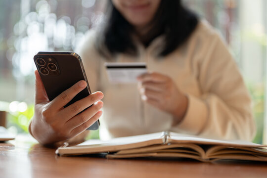 Cropped image of a happy and satisfied Asian woman enjoys shopping online on her smartphone.