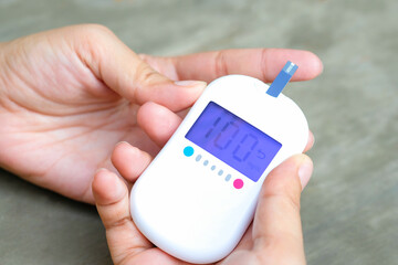 hand of woman check diabetes and high blood glucose monitor with digital pressure gauge. Healthcare and Medical concept.