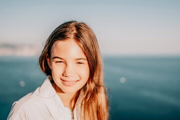 Adorable teenage girl outdoors enjoying sunset at beach on summer day. Close up portrait of smiling...