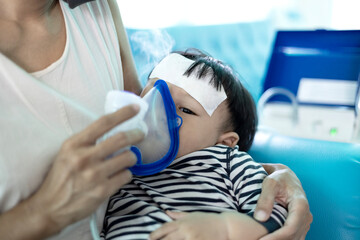 Mother Helping Little Son Using Nebulizer During Inhalation.