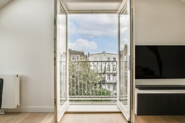 an open door leading to a balcony with a view of the city and trees in the distance, taken from inside