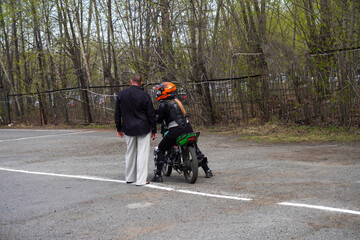 Fototapeta premium A young woman is learning to ride a motorbike in a motorcycle school. She is taught by a teacher