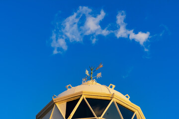Fototapeta na wymiar 朝日を浴びる灯台の風向計と青空の流れる雲20231021