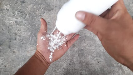 Someone puts powder on her hand. Smooth and fragrant baby powder in a white plastic bottle