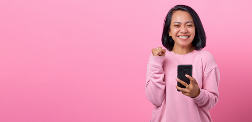 Portrait excited young woman with smartphone on pink background