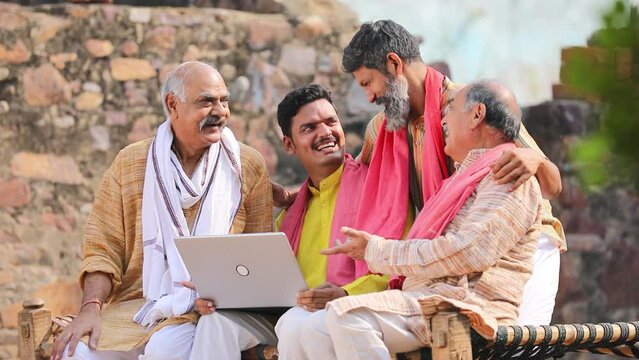 Indian villagers setting at in front of home and using laptop.