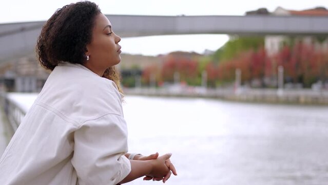 Sad African American woman looking at river. Depression and loneliness concept