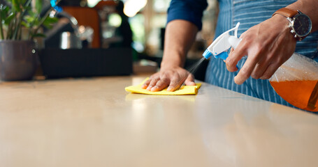 Waiter, hands and cleaning table in restaurant for dust, bacteria and dirt with cloth, spray or...