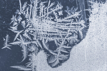 White frost is on a window glass, natural winter background