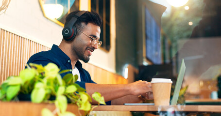 Happy man in cafe with headphones, typing on laptop and remote work, reading email and web in restaurant. Computer, freelancer smile and copywriter in coffee shop, listen to music and radio at table - obrazy, fototapety, plakaty