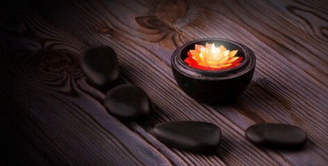 black stones and a candle on wooden background