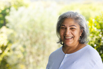 Portrait of happy biracial senior woman laughing in sunny garden, copy space