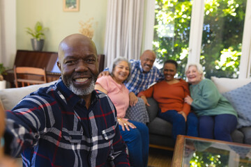 Happy african american senior man doing selfie and smiling in sunny living room, copy space