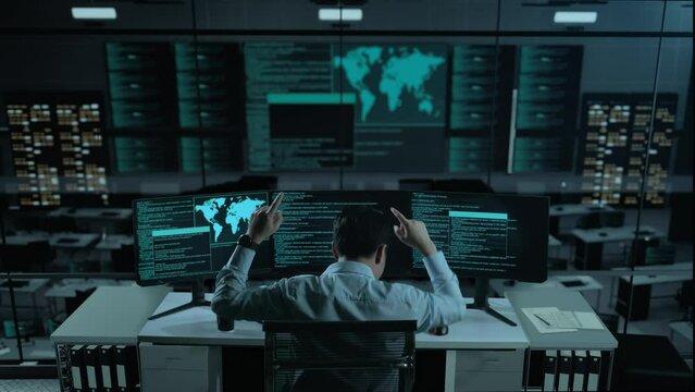 Back View Of Happy Asian Man Developer Celebrating And Dancing While Write Code With Multiple Computer Screens In The Office
