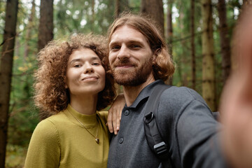 Selfie portrait of young couple smiling at camera during their hiking in the forest