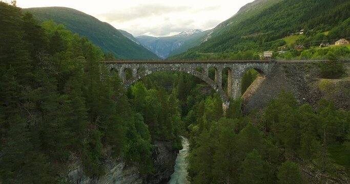 Rauma river flows under Kylling Bru stone railway bridge, Verma, Norway. Aerial