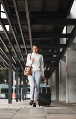 Phone, travel and luggage with a business woman in an airport parking lot walking outdoor in the city. Mobile, suitcase and commute with a young corporate employee on an international trip for work