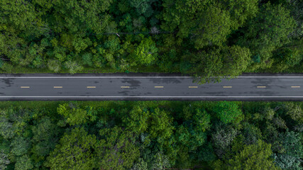 Aerial view over  forest road with asphalt road and forest, Road in the middle of the forest up to mountain, Countryside road passing through the green forrest and mountain.