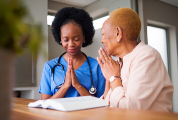 Healthcare, black woman nurse and patient praying together while reading the bible in an old age...