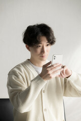 スマホを見るニットを着た男性　スマホをタップする