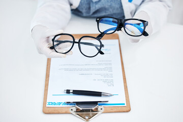 Hands, vision and glasses test with consulting and healthcare contract in consultation with support. Hospital, lens care and paperwork with doctor and ophthalmologist holding eyewear in clinic © Joshua A/peopleimages.com