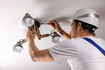 handyman services. electrician installing ceiling lamp at home