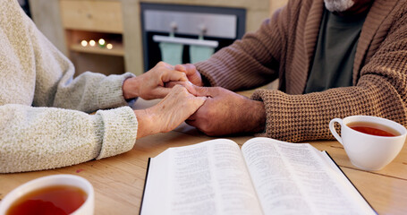 Bible study, senior couple and holding hands for praying, religion and closeup in home for...