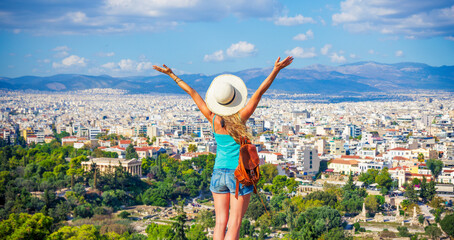 Happy woman tourist with arms raised up enjoying panoramic view of Athens city in Greece