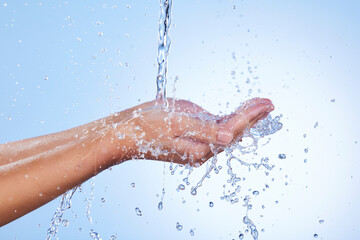Hands, water splash and wash for skincare hygiene or hydration against a blue studio background. Closeup of hand with liquid drops, shower or washing for clean wellness or natural sustainability - obrazy, fototapety, plakaty