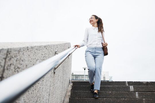 Thinking, woman and walking on city building steps happy, smile and looking while traveling. Travel, walk and business lady smile for commute, memory and enjoying solo trip in New York outdoor