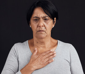 Fototapeta premium Fear, senior and a woman with a heart attack on a black background with healthcare anxiety. Emergency, sad and an elderly person feeling chest for pain, sick or medical scare isolated on a backdrop
