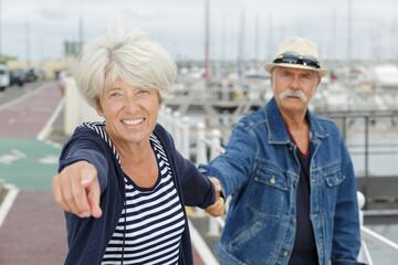 mature man and woman walking by sea and pointing upwards