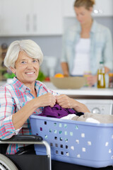 senior woman in wheelchair with a laundry basket