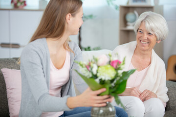 a professional caretaker giving flowers to senior woman
