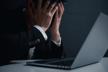 Serious  businessman using laptop computer and  sitting at workplace in office. Business and entrepreneurship problems concept