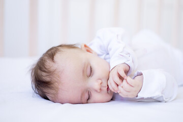 baby girl sleeping on a bed on a white cotton bed, sweet sleep cute newborn baby baby at home in a crib close-up