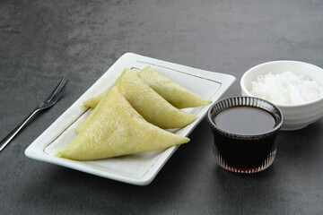 Lupis or Lopis, a traditional Indonesian food made from sticky rice and wrapped in banana leaves. Served with grated coconut and liquid brown sugar. 
