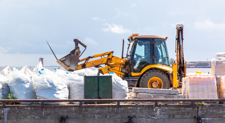 Tractor loading bags on a pier by the sea