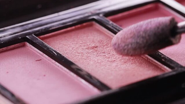 Applying eye shadow to a makeup brush. Modern cosmetics for the face, macro, Slow motion