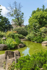 Garden of Russian-Japanese friendship with unique Japanese plants and architectural forms. Pond with emerald water and stone banks. Garden is decorated with sculptures and Japanese-style buildings.