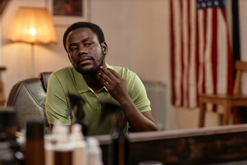 African American man looking at mirror and admiring himself in barber shop