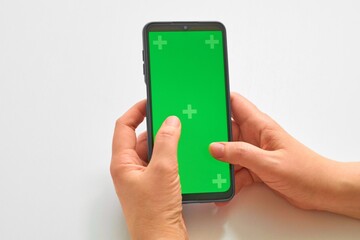 Elderly woman hands holding smartphone with green screen. Mock up mobile. The chromakey. Green screen