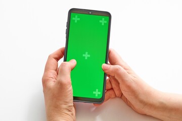Elderly woman hands holding smartphone with green screen. Mock up mobile. The chromakey. Green screen
