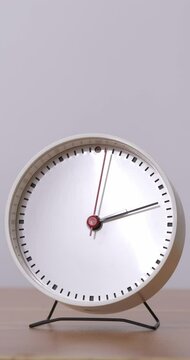 4K footage vertical video front view CU Time-lapse, White alarm clock sits on the table saying 2:00 p.m.
