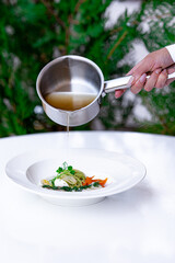 woman's hand pours soup into a plate