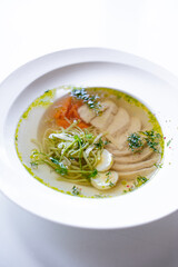 soup with meat and herbs in a white plate on the windowsill