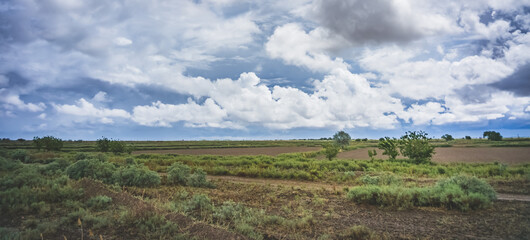 Fototapeta na wymiar Panorama of a cloudy cloudy rain sky with cumulus clouds of various levels and fields
